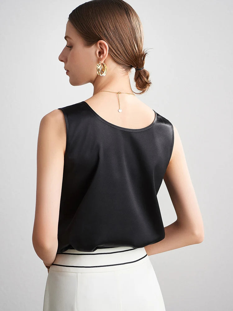 A woman wearing a black sleeveless silk top with a plain background