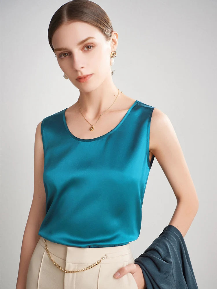 A woman wearing a teal sleeveless silk top against a plain background